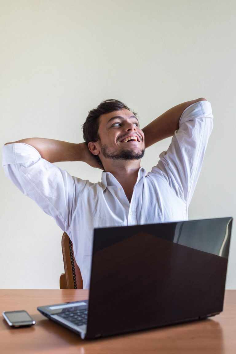 Person at desk with laptop computer smiling and relaxed